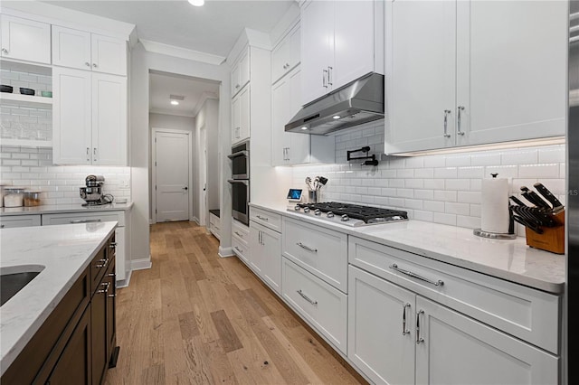 233 Yorkshire Dr, Saint Augustine, FL 32092 - kitchen featuring stainless steel gas stovetop, under cabinet range hood, crown molding, white cabinetry, and tasteful backsplash