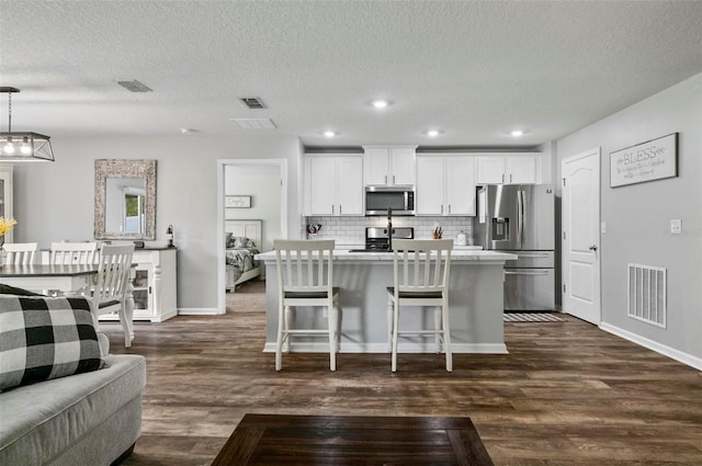 7 Grand Par Ct, Bunnell, FL 32110 - kitchen featuring appliances with stainless steel finishes, dark wood-type flooring, an island with sink, light countertops, and a textured ceiling
