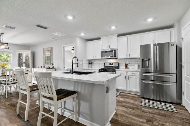 7 Grand Par Ct, Bunnell, FL 32110 - kitchen featuring appliances with stainless steel finishes, a kitchen island with sink, a textured ceiling, dark wood finished floors, and backsplash