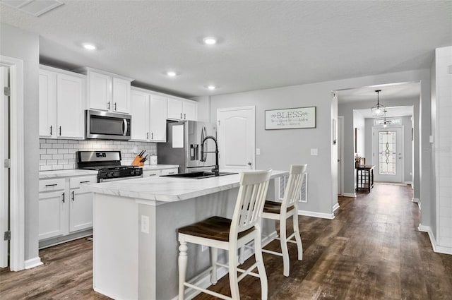 7 Grand Par Ct, Bunnell, FL 32110 - kitchen with stainless steel appliances, a center island with sink, dark wood-style floors, tasteful backsplash, and a kitchen bar