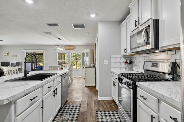 7 Grand Par Ct, Bunnell, FL 32110 - kitchen with appliances with stainless steel finishes, white cabinetry, tasteful backsplash, dark wood-style floors, and a center island with sink