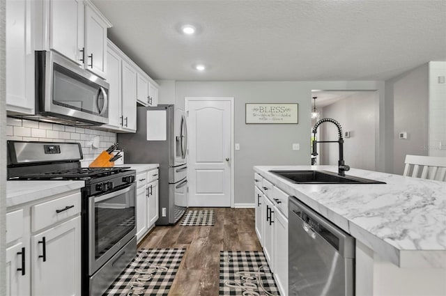 7 Grand Par Ct, Bunnell, FL 32110 - kitchen with stainless steel appliances, white cabinets, dark wood-type flooring, tasteful backsplash, and a kitchen island with sink