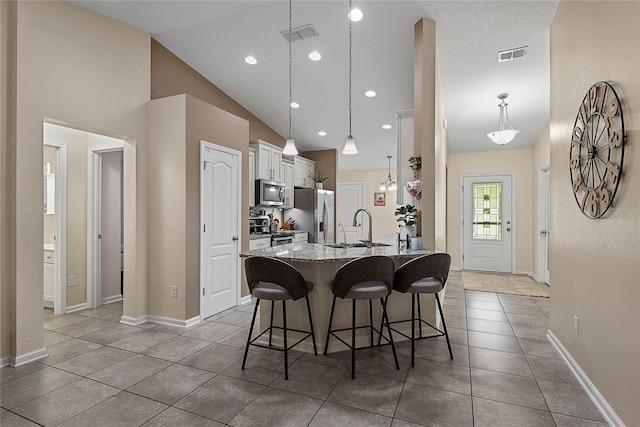 166 Midway Park Dr, Saint Augustine, FL 32084 - kitchen with a breakfast bar, stainless steel appliances, white cabinetry, lofted ceiling, and light tile patterned flooring