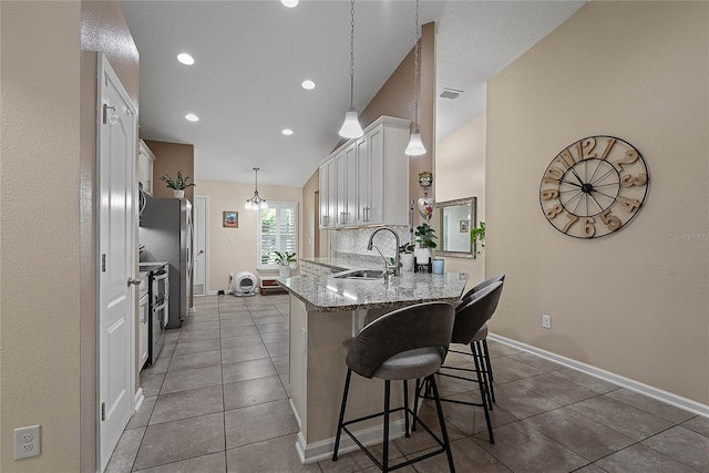 166 Midway Park Dr, Saint Augustine, FL 32084 - kitchen featuring a peninsula, a breakfast bar area, tile patterned flooring, white cabinets, and light stone countertops