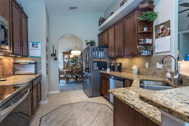 25 Raintree Cir, Palm Coast, FL 32164 - kitchen featuring stainless steel appliances, open shelves, backsplash, light stone counters, and arched walkways