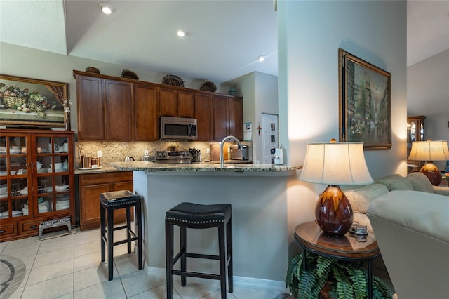 25 Raintree Cir, Palm Coast, FL 32164 - kitchen with appliances with stainless steel finishes, vaulted ceiling, backsplash, a breakfast bar area, and stone counters