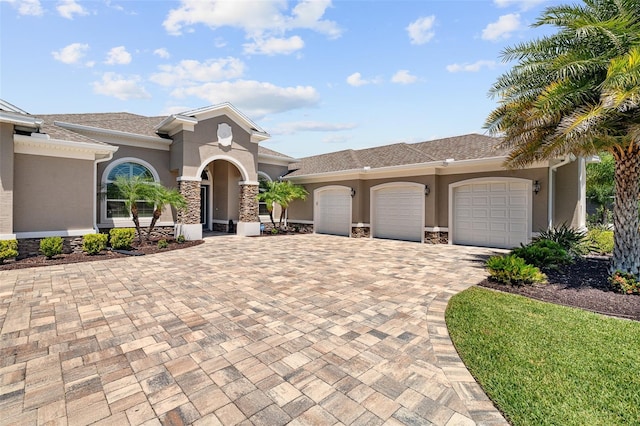 4 Old Oak Dr N, Palm Coast, FL 32137 - mediterranean / spanish house with stucco siding, an attached garage, decorative driveway, and stone siding