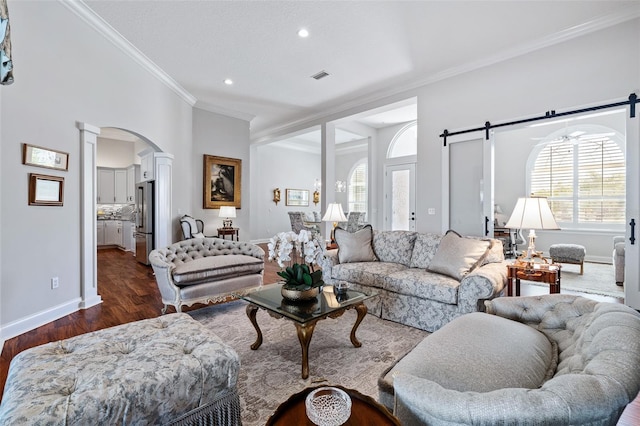 4 Old Oak Dr N, Palm Coast, FL 32137 - living room featuring a barn door, decorative columns, dark wood-style flooring, ornamental molding, and arched walkways