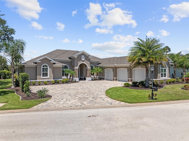 4 Old Oak Dr N, Palm Coast, FL 32137 - mediterranean / spanish home featuring stucco siding, decorative driveway, an attached garage, a front lawn, and stone siding