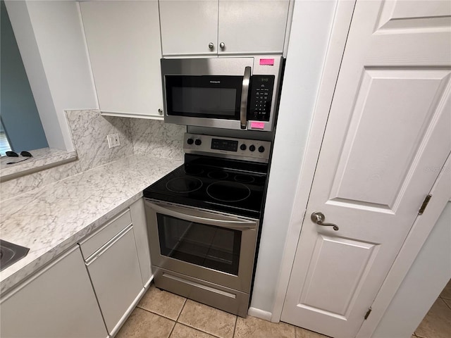 59 Rivers Edge Ln Unit 59, Palm Coast, FL 32137 - kitchen with appliances with stainless steel finishes, light countertops, white cabinets, light tile patterned floors, and decorative backsplash