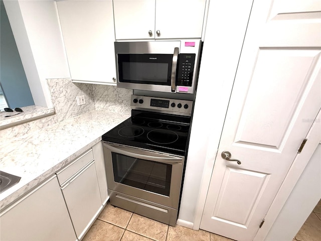 59 Rivers Edge Ln Unit 59, Palm Coast, FL 32137 - kitchen featuring appliances with stainless steel finishes, white cabinetry, light countertops, light tile patterned flooring, and backsplash