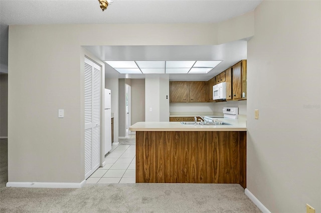 14 Oakmont Ct Unit 14, Palm Coast, FL 32137 - kitchen featuring white appliances, light countertops, light colored carpet, and brown cabinets
