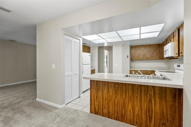 14 Oakmont Ct Unit 14, Palm Coast, FL 32137 - kitchen featuring white appliances, light colored carpet, a peninsula, brown cabinetry, and light countertops