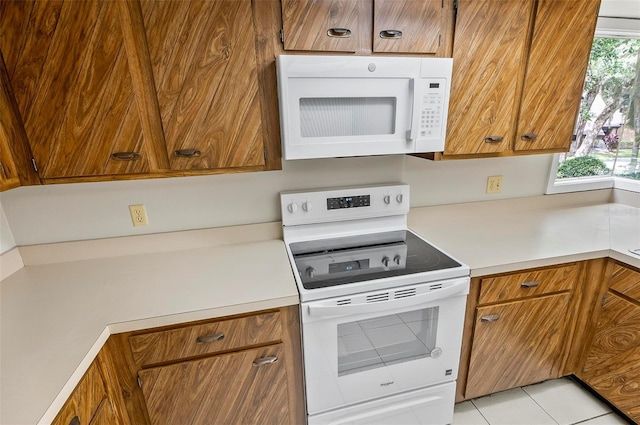 14 Oakmont Ct Unit 14, Palm Coast, FL 32137 - kitchen with white appliances, brown cabinetry, light countertops, and light tile patterned floors