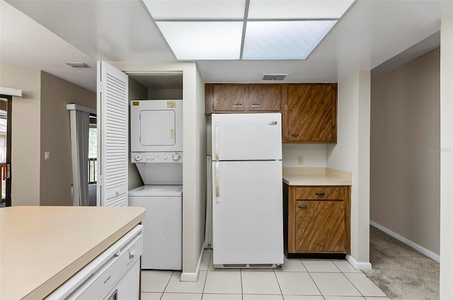 14 Oakmont Ct Unit 14, Palm Coast, FL 32137 - kitchen with freestanding refrigerator, stacked washer / drying machine, light countertops, light tile patterned flooring, and brown cabinetry
