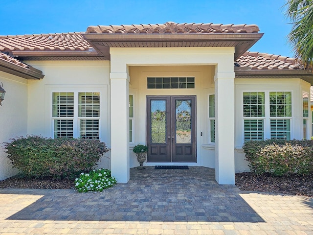 145 Heron Dr, Palm Coast, FL 32137 - view of exterior entry featuring french doors, a tiled roof, and stucco siding