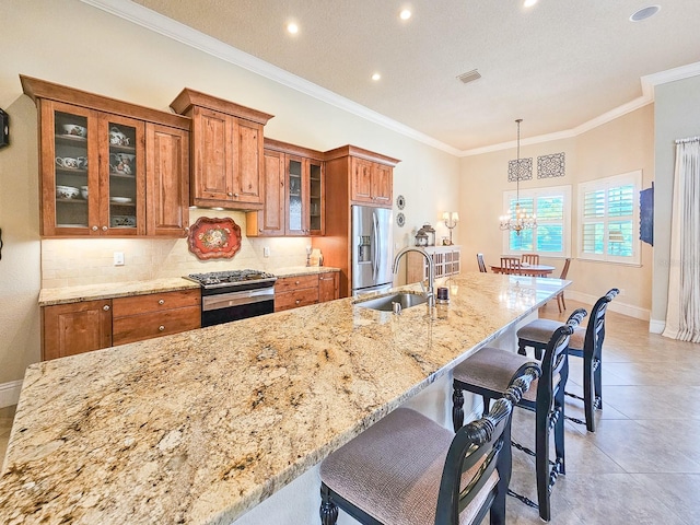 145 Heron Dr, Palm Coast, FL 32137 - kitchen featuring appliances with stainless steel finishes, brown cabinetry, ornamental molding, a chandelier, and a breakfast bar