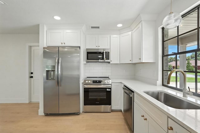 43 Courtney Pl, Palm Coast, FL 32137 - kitchen with appliances with stainless steel finishes, light wood-style floors, white cabinets, tasteful backsplash, and recessed lighting