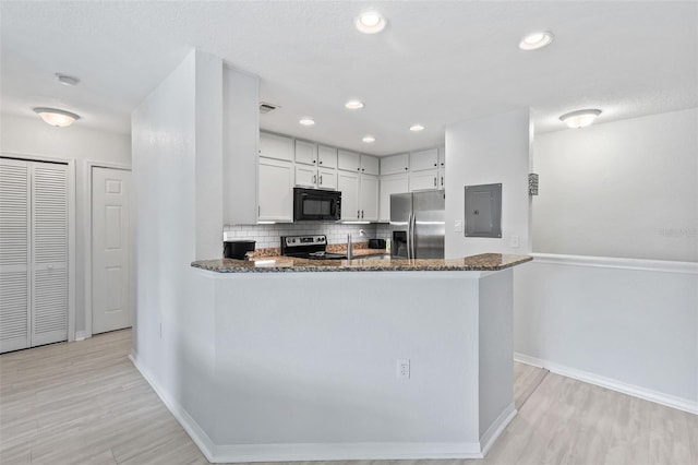 4600 E Moody Blvd Unit 14O, Bunnell, FL 32110 - kitchen featuring appliances with stainless steel finishes, electric panel, dark stone counters, decorative backsplash, and light wood-style flooring