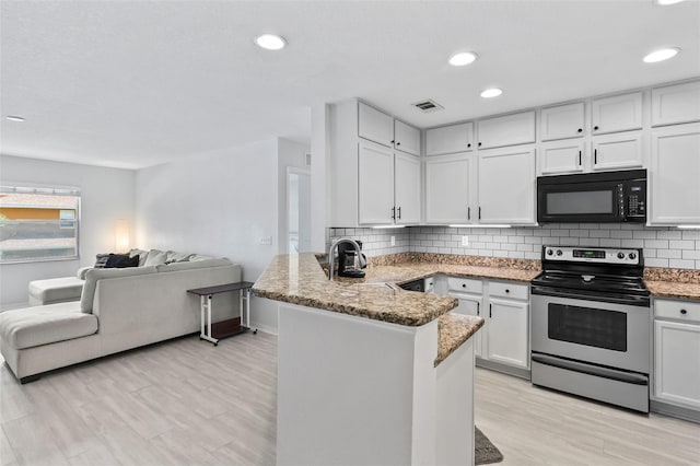 4600 E Moody Blvd Unit 14O, Bunnell, FL 32110 - kitchen with electric stove, black microwave, open floor plan, a peninsula, and white cabinets