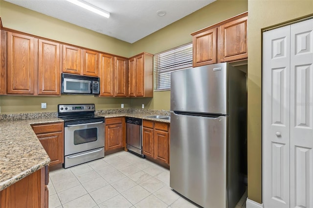 4600 E Moody Blvd Unit 14O, Bunnell, FL 32110 - kitchen with stainless steel appliances, brown cabinetry, light tile patterned floors, and light stone counters