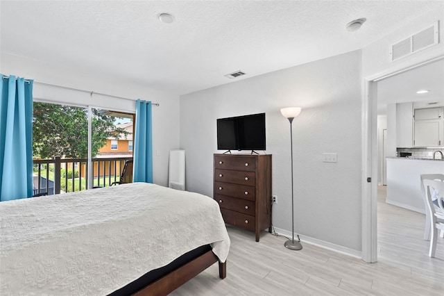 4600 E Moody Blvd Unit 14O, Bunnell, FL 32110 - bedroom with access to outside, light wood-style floors, and a textured ceiling