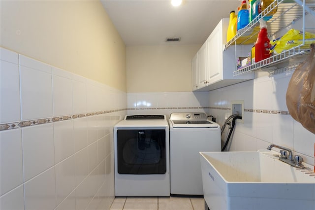 25 Raintree Pl, Palm Coast, FL 32164 - laundry area featuring tile walls, cabinet space, washer and clothes dryer, and light tile patterned floors