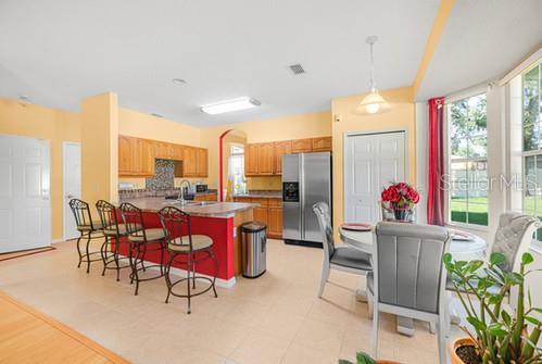 7 Flint Pl, Palm Coast, FL 32137 - kitchen with stainless steel refrigerator with ice dispenser, a breakfast bar, a peninsula, brown cabinets, and decorative light fixtures