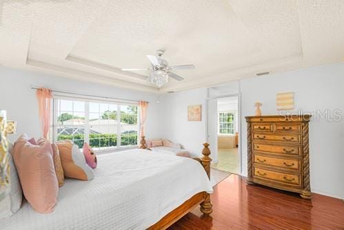 7 Flint Pl, Palm Coast, FL 32137 - bedroom featuring a tray ceiling, wood finished floors, a ceiling fan, and a textured ceiling