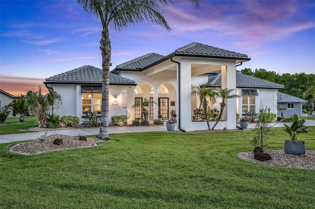 33 Crystal Bay Ct, Palm Coast, FL 32137 - back of property at dusk featuring stucco siding, a lawn, and a tile roof
