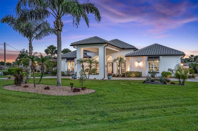 33 Crystal Bay Ct, Palm Coast, FL 32137 - back of property at dusk featuring stucco siding and a lawn
