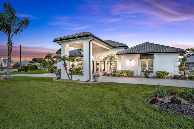 33 Crystal Bay Ct, Palm Coast, FL 32137 - back of property at dusk featuring a lawn, a tile roof, and stucco siding