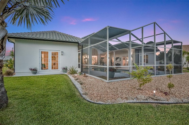 33 Crystal Bay Ct, Palm Coast, FL 32137 - back of house featuring a tile roof, stucco siding, a lawn, and glass enclosure