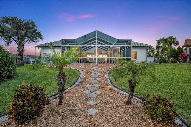 33 Crystal Bay Ct, Palm Coast, FL 32137 - back of house at dusk with stucco siding, a lawn, and a lanai