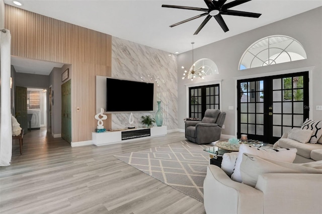 33 Crystal Bay Ct, Palm Coast, FL 32137 - living room featuring light wood finished floors, french doors, a ceiling fan, a high ceiling, and an accent wall