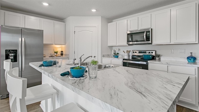 8 Mill Wheel Ct S, Palm Coast, FL 32137 - kitchen featuring appliances with stainless steel finishes, a center island with sink, a breakfast bar, white cabinetry, and dark wood-style flooring