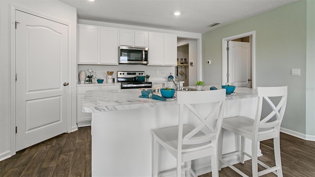 8 Mill Wheel Ct S, Palm Coast, FL 32137 - kitchen with appliances with stainless steel finishes, dark wood-style flooring, light countertops, white cabinetry, and recessed lighting