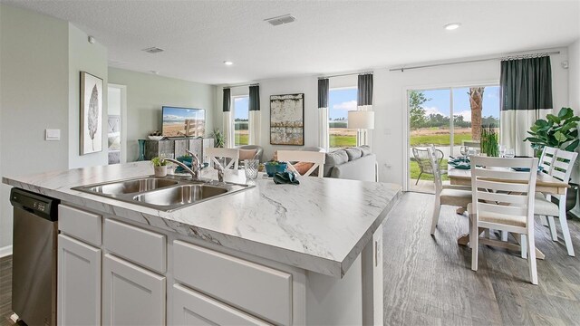 8 Mill Wheel Ct S, Palm Coast, FL 32137 - kitchen with stainless steel dishwasher, open floor plan, light wood-type flooring, an island with sink, and white cabinetry