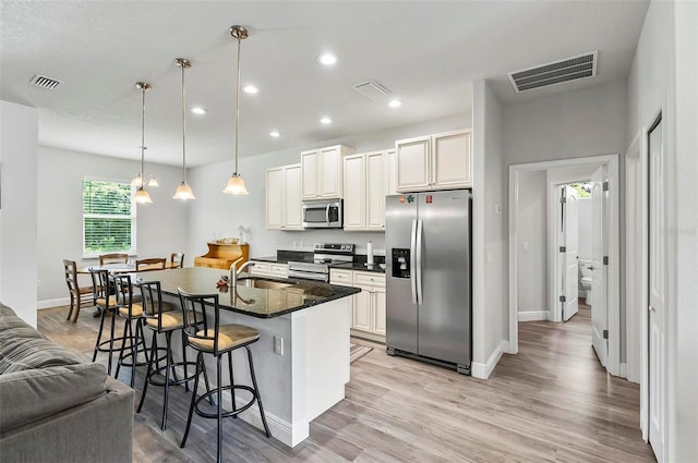 9 Elder Pl, Palm Coast, FL 32164 - kitchen featuring stainless steel appliances, a breakfast bar, light wood finished floors, recessed lighting, and a kitchen island with sink