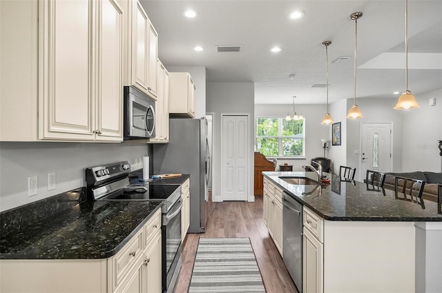 9 Elder Pl, Palm Coast, FL 32164 - kitchen with appliances with stainless steel finishes, wood finished floors, a kitchen island with sink, recessed lighting, and dark stone countertops