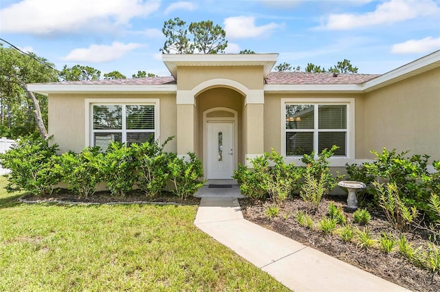 9 Elder Pl, Palm Coast, FL 32164 - doorway to property with a lawn, stucco siding, and roof with shingles