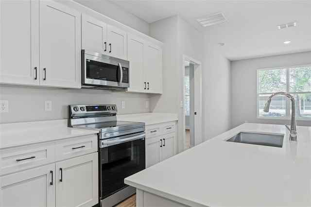 1 Barbera Ln, Palm Coast, FL 32137 - kitchen with stainless steel appliances, white cabinetry, light countertops, and light wood-style flooring