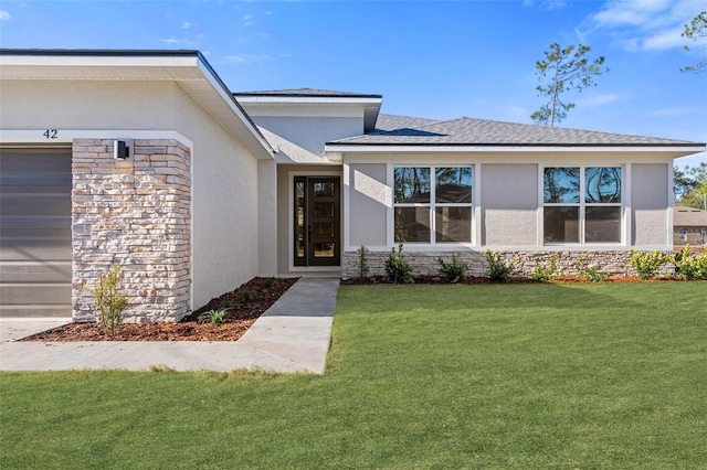 1 Barbera Ln, Palm Coast, FL 32137 - view of exterior entry with stucco siding, a yard, stone siding, and a shingled roof