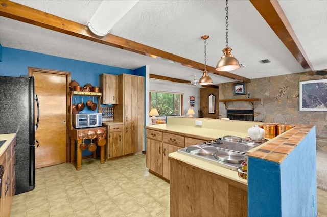 2940 Sunset Dr, New Smyrna Beach, FL 32168 - kitchen with beamed ceiling, freestanding refrigerator, light countertops, decorative light fixtures, and a stone fireplace