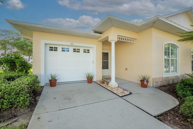 47 Summerwind Cir, Palm Coast, FL 32137 - doorway to property with stucco siding, a garage, and driveway