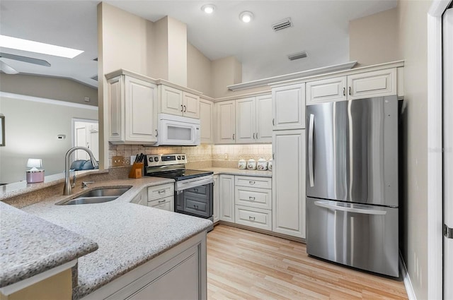 5 Wilksboro Pl, Palm Coast, FL 32164 - kitchen with appliances with stainless steel finishes, a skylight, vaulted ceiling, backsplash, and a peninsula