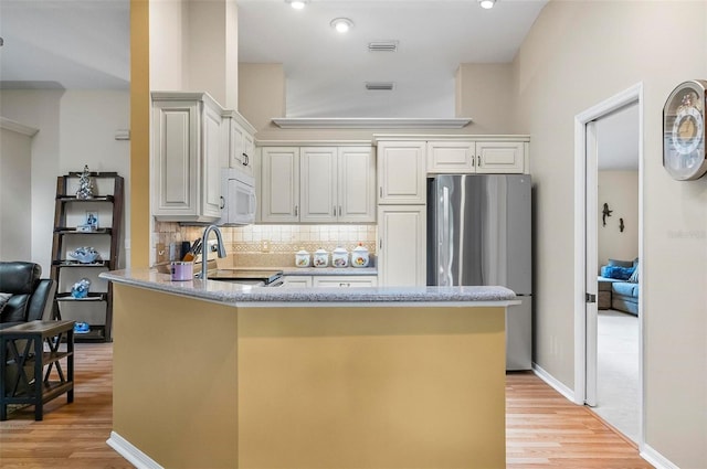 5 Wilksboro Pl, Palm Coast, FL 32164 - kitchen featuring freestanding refrigerator, range with electric stovetop, a peninsula, light wood-type flooring, and tasteful backsplash