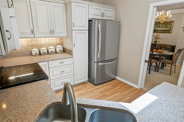 5 Wilksboro Pl, Palm Coast, FL 32164 - kitchen featuring freestanding refrigerator, a chandelier, light wood-style floors, white cabinets, and decorative backsplash