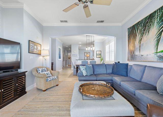 200 Cinnamon Beach Way Unit 131, Palm Coast, FL 32137 - living room with a ceiling fan, light tile patterned flooring, crown molding, a chandelier, and arched walkways