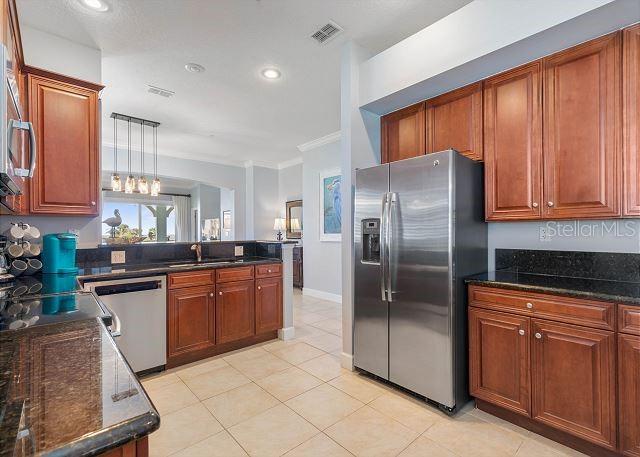 200 Cinnamon Beach Way Unit 131, Palm Coast, FL 32137 - kitchen with stainless steel appliances, ornamental molding, a peninsula, light tile patterned floors, and dark stone counters